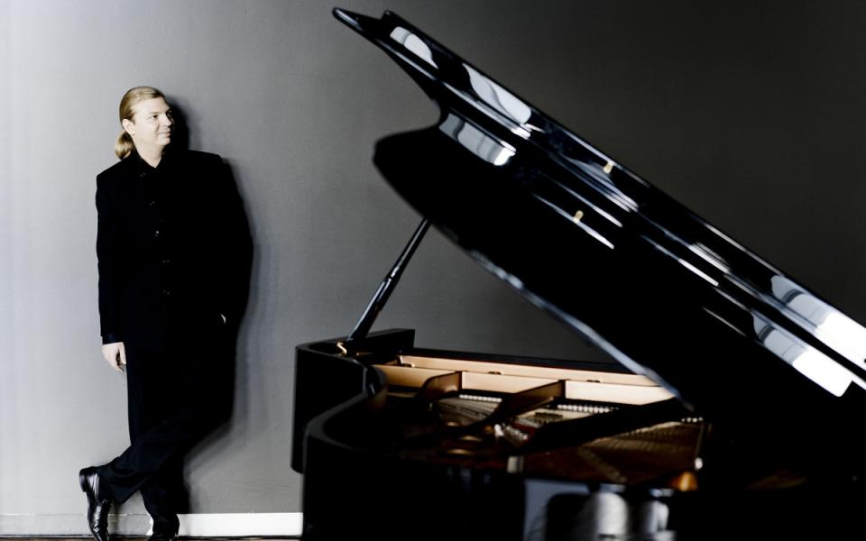 Denis Kozukhin standing next to a piano