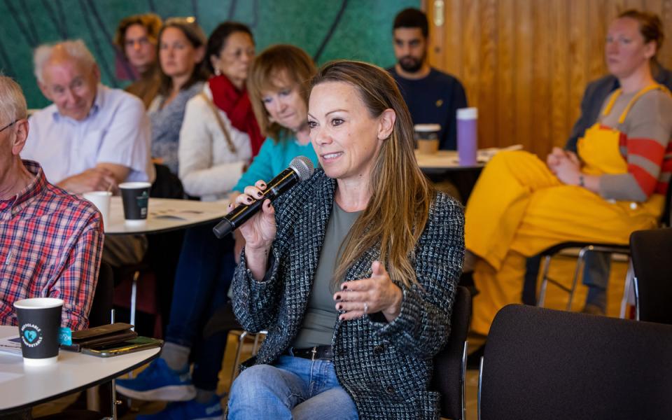 Woman holding a microphone with other audience members in discussion