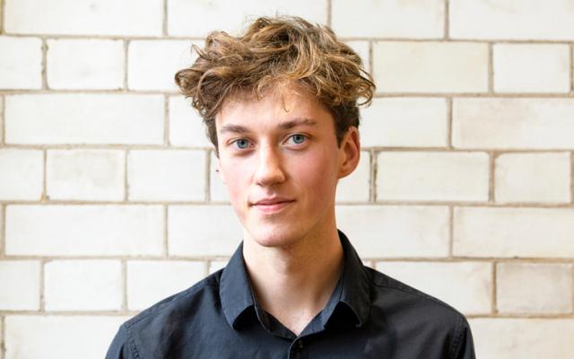 Cellist Silvestrs Kalnins in black suit smiling.