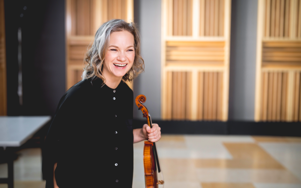 Hilary Hahn holding her violin and smiling