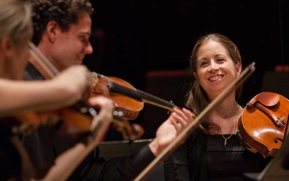 Philharmonia string players on stage in fun conversation.